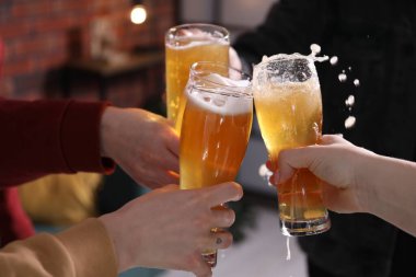Arkadaşlar bira bardaklarını tokuşturur, yakın plan