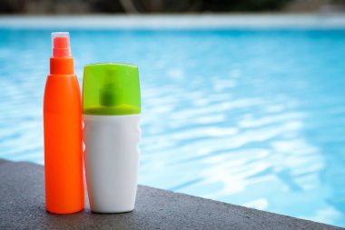 Yüzme havuzu yakınlarındaki taş yüzeyde güneş koruma ürünleri şişeleri, metin için yer