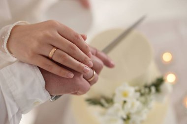 Evli çift içeride bıçakla lezzetli bir düğün pastası kesiyor.