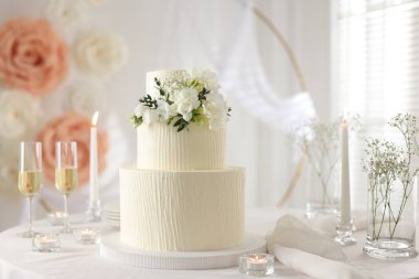 Çiçek desenli nefis düğün pastası ve kapalı bir masada şampanya bardakları.