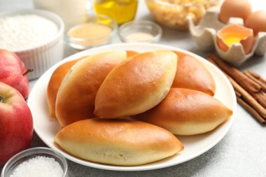 Lezzetli fırında köfteler ve malzemeler açık gri masada, yakın plan.