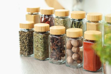 Kapalı alanda, ahşap masadaki kavanozlardaki farklı aromatik baharatlar.