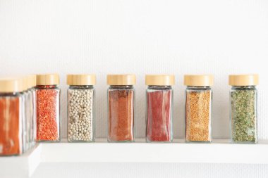 Beyaz raflardaki kavanozlardaki farklı aromatik baharatlar.