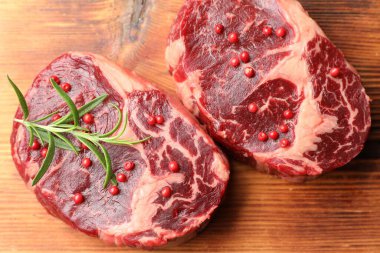 Ahşap masada çiğ et ve baharat parçaları.