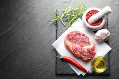 Bir parça çiğ et ve baharat siyah masada, düz yerde. Metin için boşluk