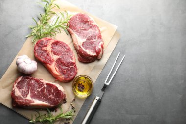 Çiğ et, baharat ve çatal parçaları gri masada, düz yerde. Metin için boşluk