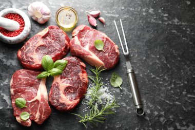 Çiğ et, baharat ve çatal. Koyu masada, düz yerde. Metin için boşluk