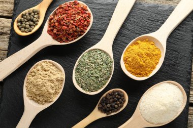 Tahta masada, düz yerde, kaşıklardaki farklı aromatik baharatlar.