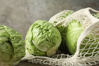 Taze lahanalar ve ahşap masada ağ torba, yakın plan.