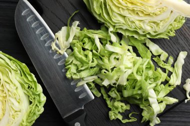 Siyah ahşap masada taze lahana ve bıçak kes, düz yat.