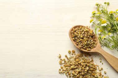 Kuru, taze papatya çiçekleri ve açık ahşap masada kaşık, düz. Metin için boşluk