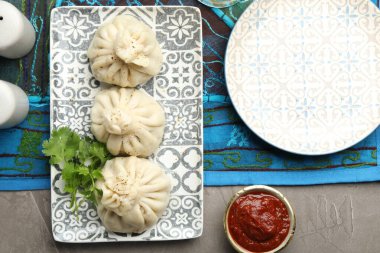 Gri masada soslu kişniş ve kişniş ile servis edilen nefis khinkali.