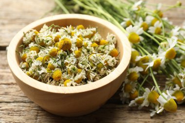 Kasede kuru papatyalar ve ahşap masada taze çiçekler, yakın plan.