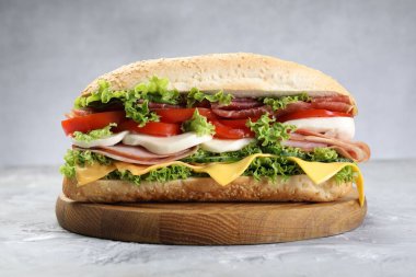 Jambonlu, peynirli ve sebzeli baget sandviç. Gri dokulu masa, yakın plan.