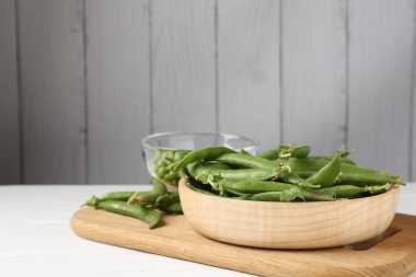 Beyaz ahşap masada taze taze yeşil bezelyeler. Metin için boşluk