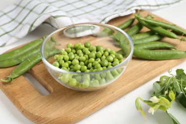 Taze taze bezelyeler beyaz ahşap masada, yakın plan.