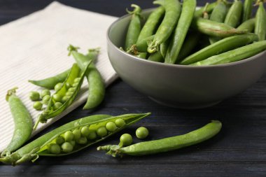 Taze taze bezelyeler siyah ahşap masada, yakın plan.