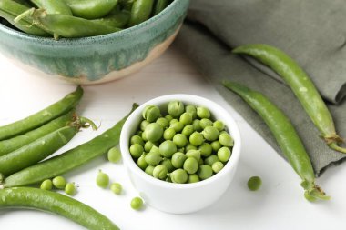 Taze taze bezelyeler beyaz ahşap masada, yakın plan.