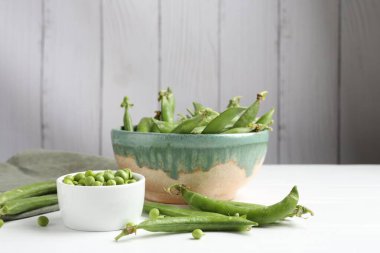 Taze taze bezelyeler beyaz ahşap masada, yakın plan.