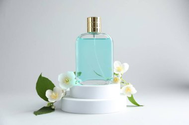 Bir şişe parfüm ve arka planda yasemin çiçekleri