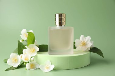 Bir şişe parfüm ve yeşil arka planda yasemin çiçekleri.