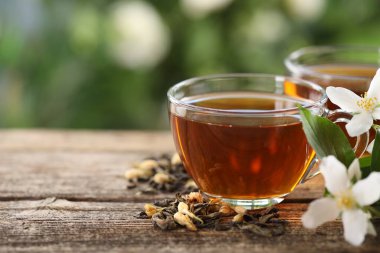 Lezzetli yasemin çayı fincanlarda, kuru yapraklar ve ahşap masada çiçekler, yakın plan. Metin için boşluk