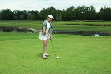 Woman with club playing golf on green course