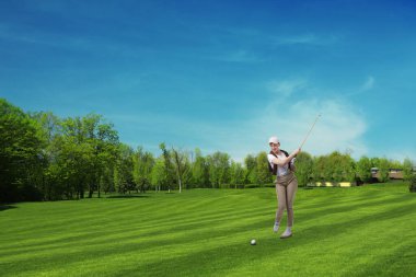 Yeşil sahada golf oynayan bir kadın.