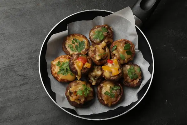 Kızartma tavasında lezzetli mantarlar, siyah masa, üst manzara.