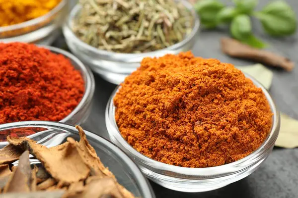 Gri masada farklı aromatik baharatlar, yakın plan.