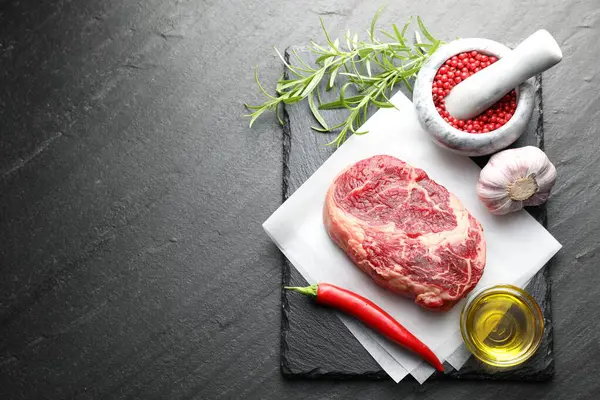 Bir parça çiğ et ve baharat siyah masada, düz yerde. Metin için boşluk