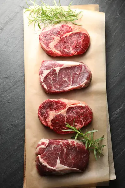 Çiğ et parçaları, biberiye ve tuz siyah masada, üst görünümde.
