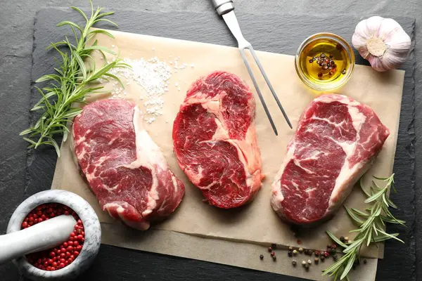 Çiğ et, baharat ve çatal parçaları siyah masaya, düz yatıyordu.