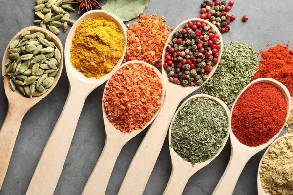 Gri masadaki kaşıklardaki farklı baharatlar düzdü.