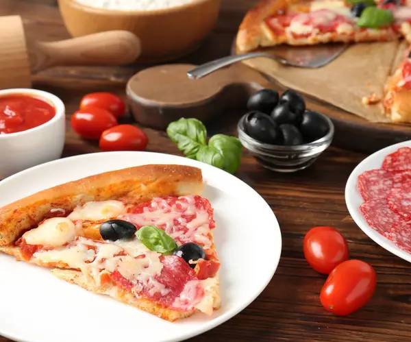 Lezzetli pizza ve malzemeler ahşap masada, yakın plan.