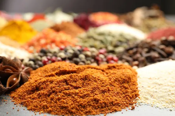Gri masada farklı aromatik baharatlar, yakın plan.