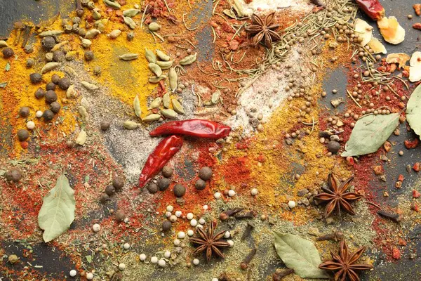 Gri masada farklı aromatik baharatlar, üst görünüm.