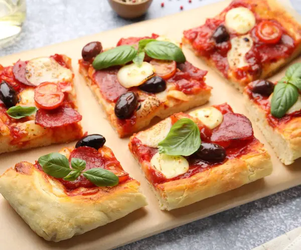 Lezzetli ev yapımı pizzalar gri masada, yakın plan.