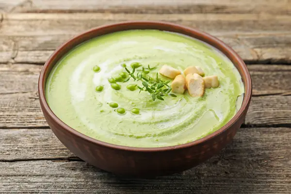 Lezzetli bezelye kremalı çorba ve ahşap masada kekik, yakın plan.
