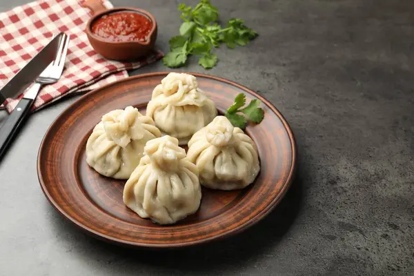 Gri masadaki sosla servis edilen lezzetli khinkali, yakın plan.