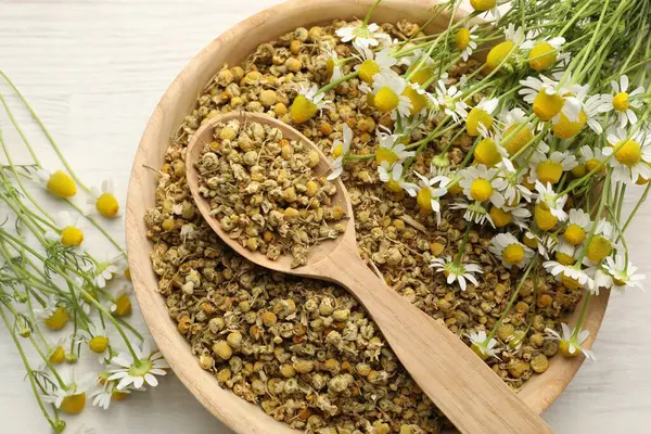 Kuru, taze papatya çiçekleri kâsede ve kaşık açık tahta masada, düz yatıyordu.