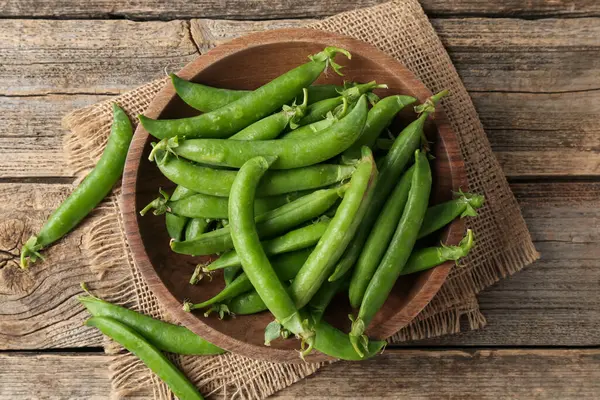 Taze taze bezelyeler ahşap masada, düz yatıyordu.
