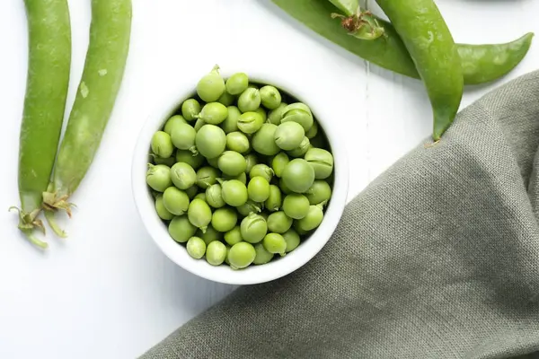 Taze taze bezelyeler beyaz ahşap masada, düz yatıyordu.
