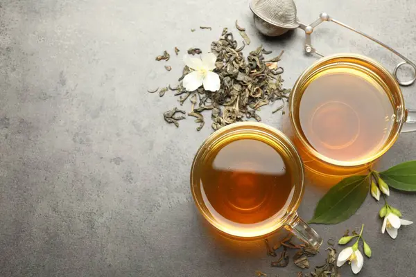 Camdan fincanlar içinde Aromatik yasemin çayı, gri masada bira ve çiçekler, düz uzanma. Metin için boşluk