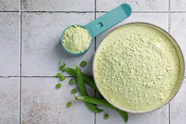 Protein tozu ve yeşil bezelyeler açık renkli masada, düz yerde. Metin için boşluk