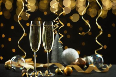 Köpüklü şarap, altın yılanbalığı şeritleri ve bulanık ışıklarla siyah arka plana karşı şenlikli dekor.