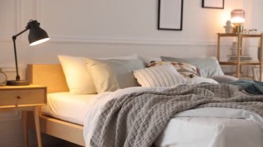 Odasında yumuşak çarşaflar ve battaniyeler olan rahat bir yatak, kamera sağa doğru hareket ediyor. Ev tekstili