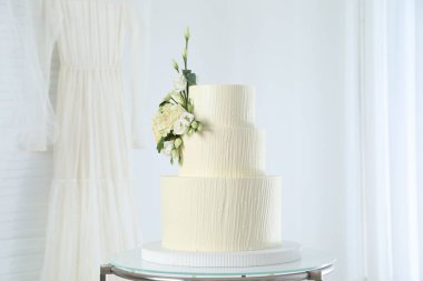 İçerideki masada çiçeklerle süslenmiş nefis düğün pastası.