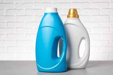 Beyaz tuğla duvara karşı gri masada yumuşatıcı şişeler.