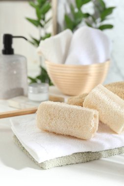 Beyaz masada farklı banyo süngeri ve havlular, yakın plan.